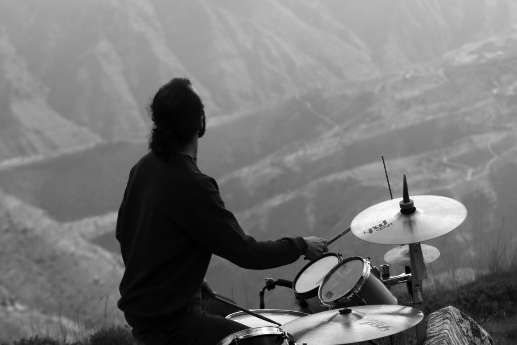 Black and white image of a drummer playing outdoors in Qazvin Mountains, Iran.
Music और Nature