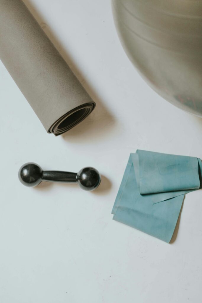Yoga mat, dumbbell, resistance band, and exercise ball arranged neatly for workout inspiration.
