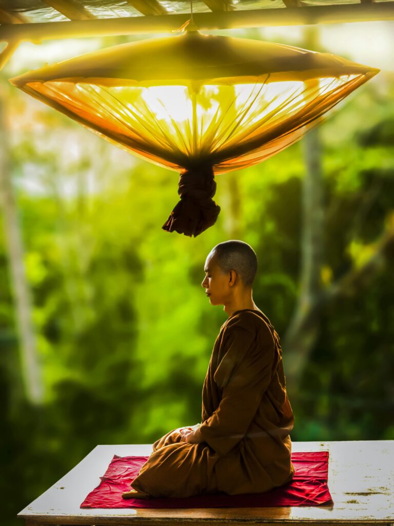 A Buddhist monk meditates outdoors, embodying peace and spirituality.