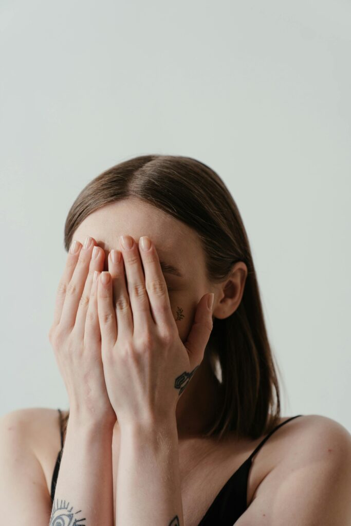 A woman covers her face with hands, exuding a sense of shyness and anonymity. Self Talk Ka Power