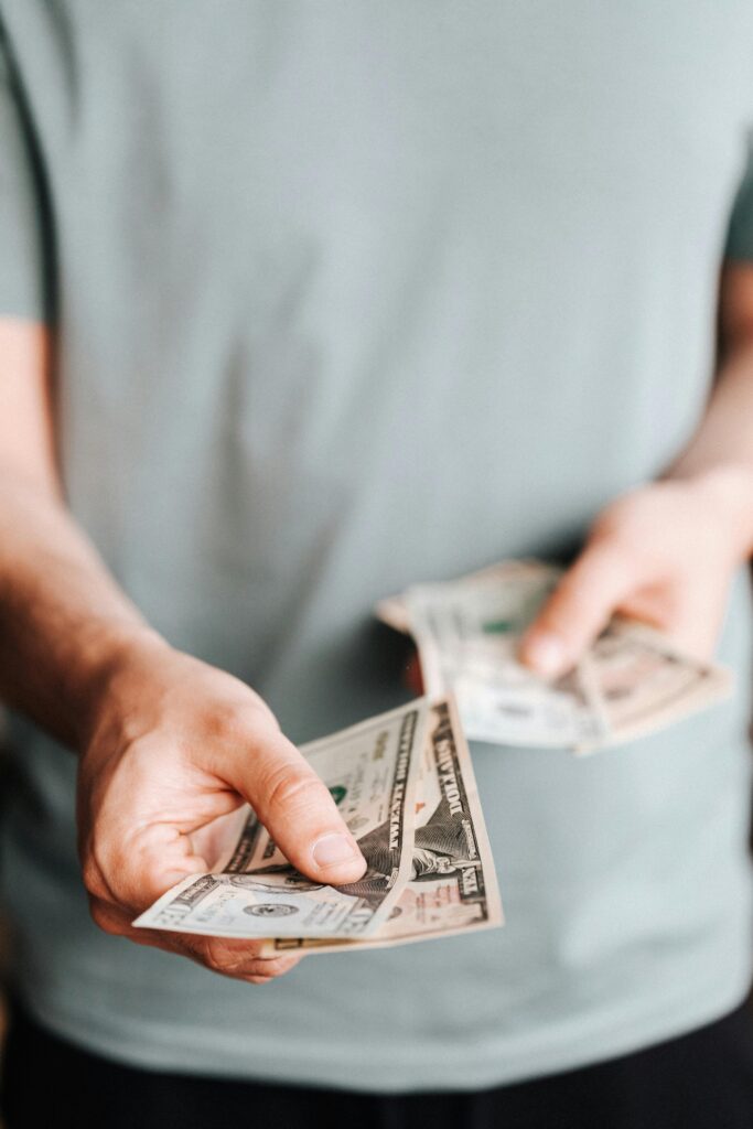 Unrecognizable male in casual clothes holding cash and paying with paper banknotes Financial Mindset