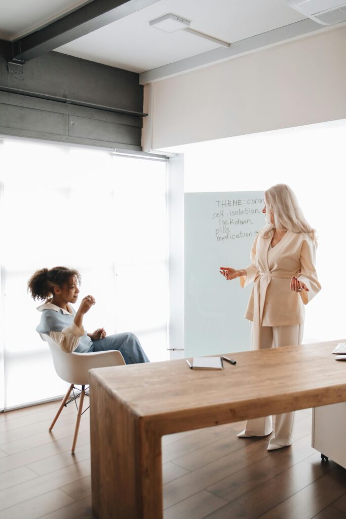 A female teacher engages with a student in a modern classroom setting.