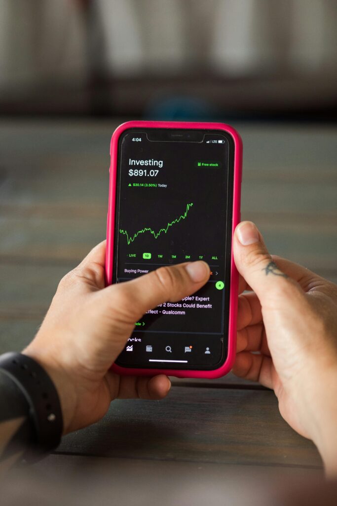 Close-up of hands holding a smartphone displaying stock market investment app. What is Investing