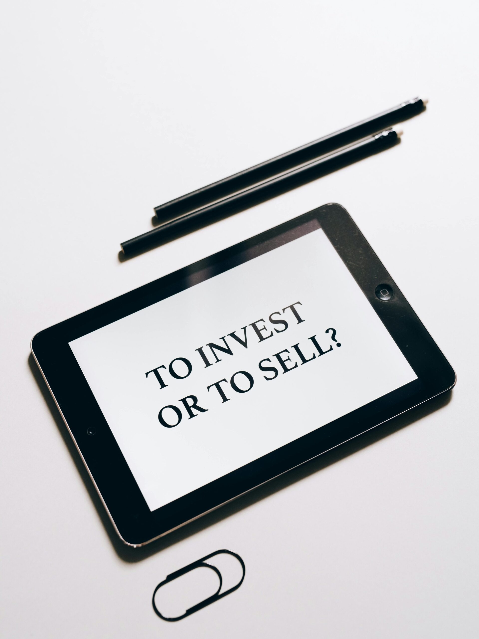 Tablet displaying 'To Invest or To Sell?' question, symbolizing investment decisions. Investment Strategy