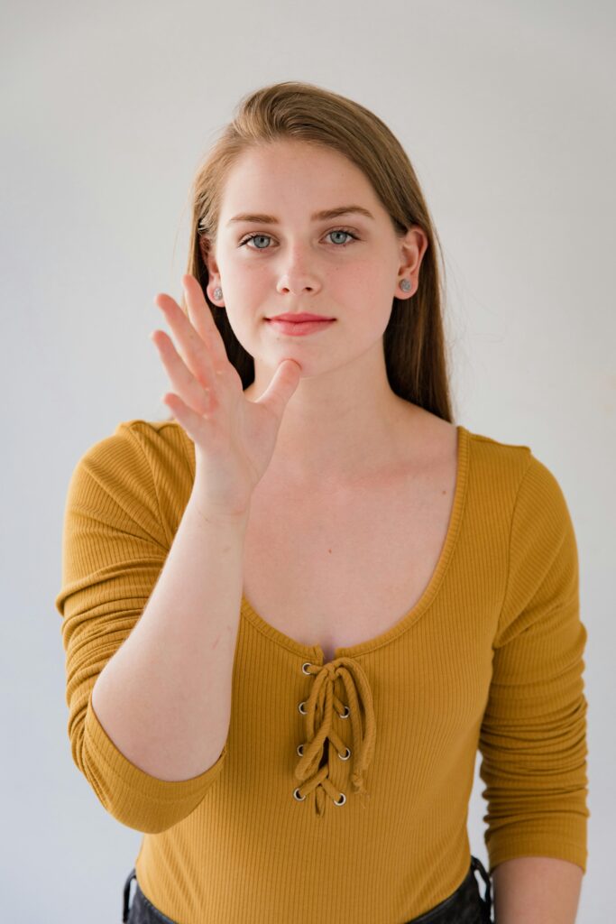 A young woman in a mustard top gestures confidently in a studio setting, focusing on communication.
Body Language