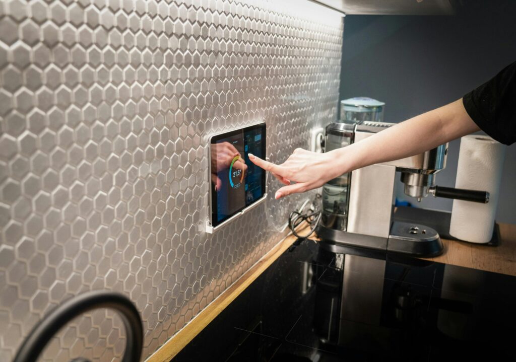 A modern kitchen with a touchscreen smart home control panel integrated into a hexagon-patterned wall.
Digital Smartness