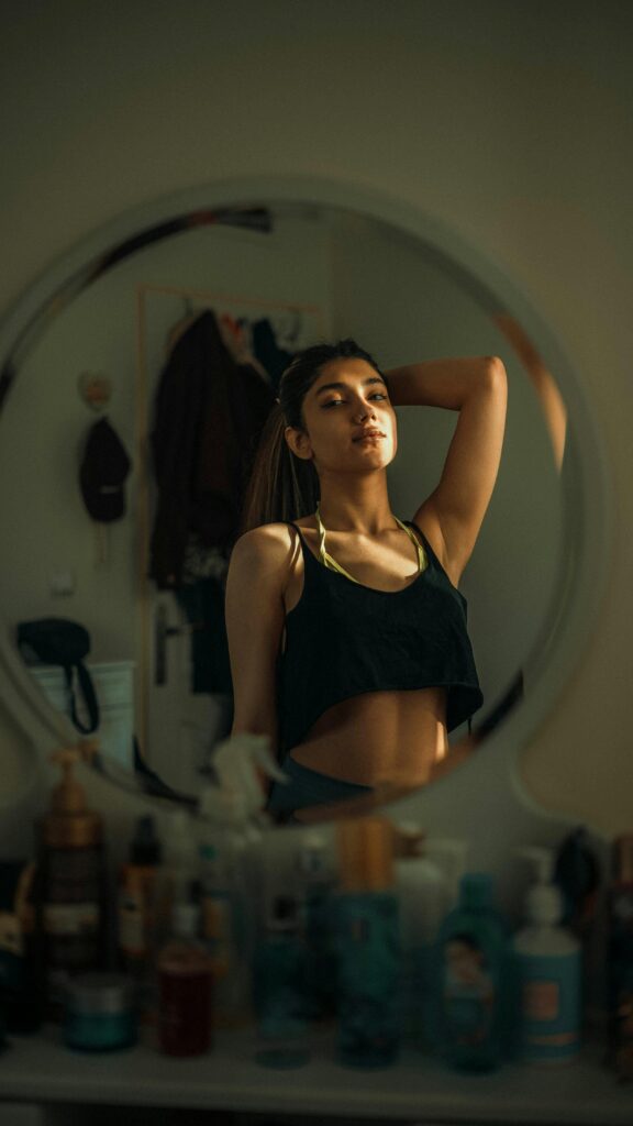 Confident young woman poses in front of a mirror, offering a fashion-forward and introspective look.