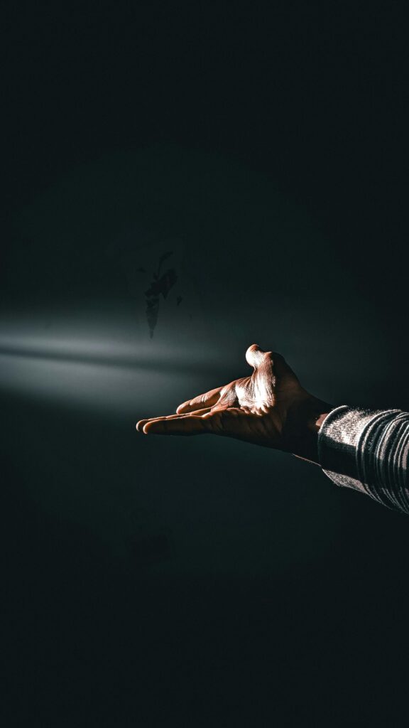 A mysterious and artistic spotlight on an open hand gesture in low light, creating a dramatic effect.
