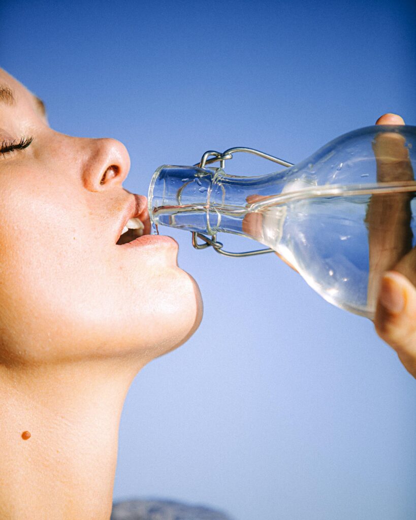 A woman drinking water from a glass bottle against a clear blue sky, emphasizing hydration.
Weight Loss Tips in Hindi