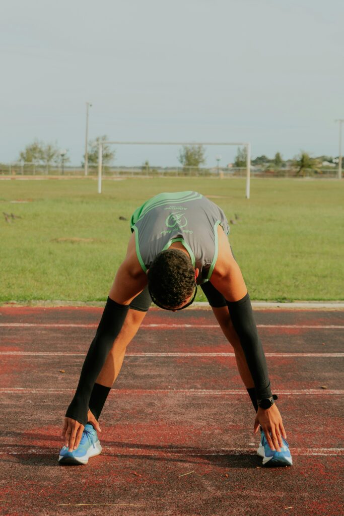 Athlete preparing for a run by stretching on a track field in Rio de Janeiro.