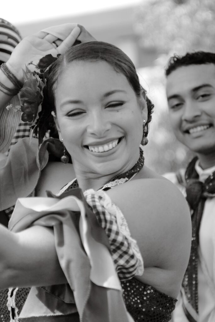 A cheerful woman in traditional Latin attire embracing cultural dance.
