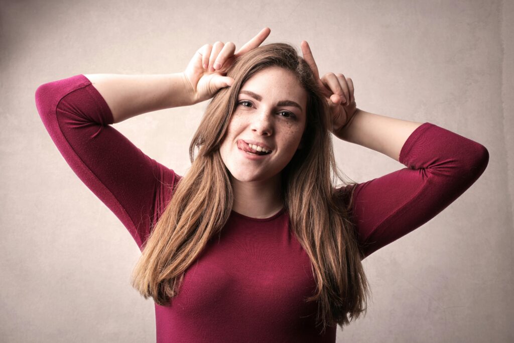 A cheerful young woman making a playful gesture in a studio portrait.