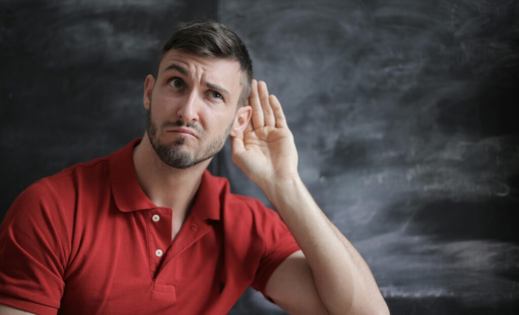 Thoughtful man listening intently against a chalkboard background in a red polo shirt.
Communication Skills Kaise Improve Kare
