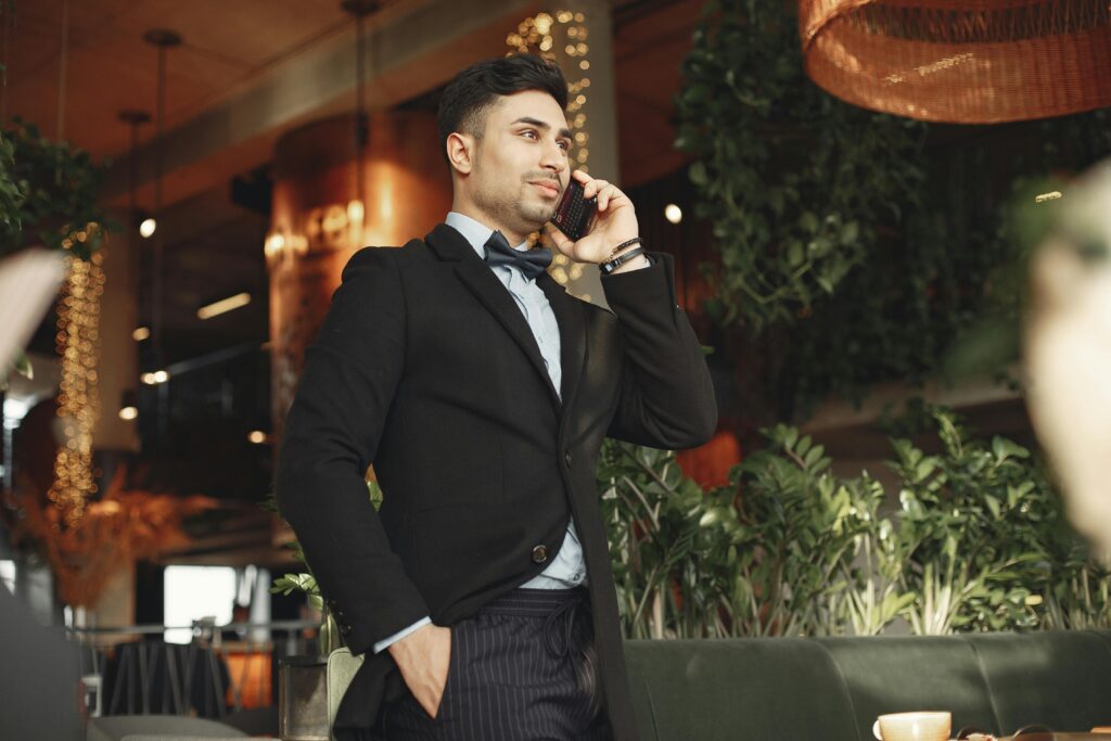 A confident businessman in a suit talks on his phone in a stylish indoor setting.