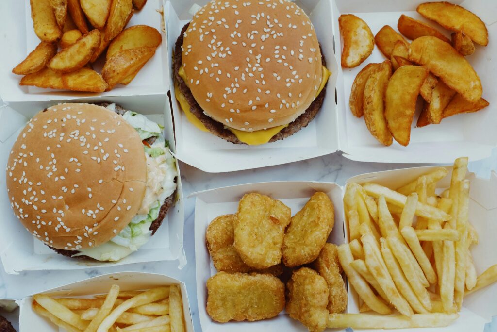 Top view of yummy junk food consisting of burgers and french fries with nuggets placed in boxes on marble background
Junk Food Chhodne Ke Tarike