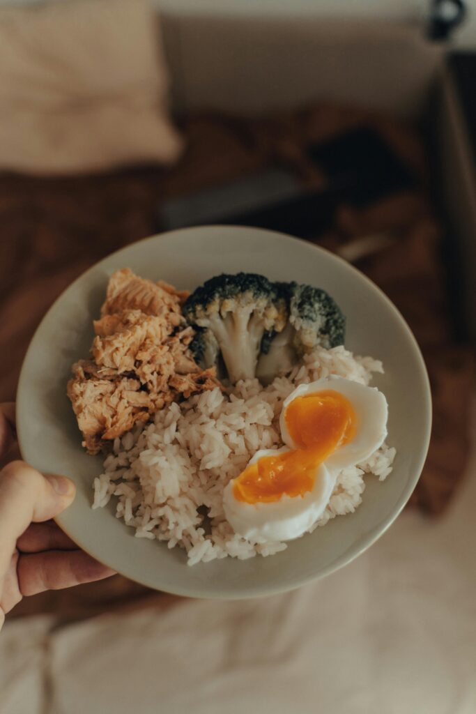 From above of crop anonymous person holding plate with homemade lunch including fried fish with broccoli and boiled egg served with rice
Fit Body Kaise Banaye 
