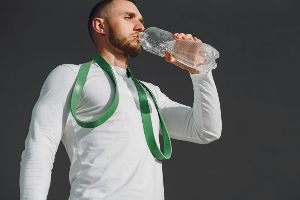 Adult man staying hydrated with bottled water in a sports setting.