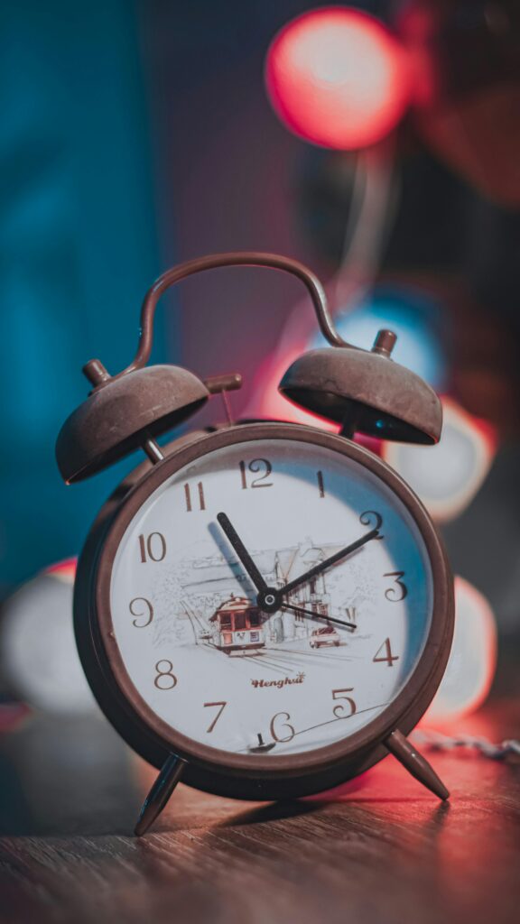 Close-up of a vintage twin bell alarm clock with a warm bokeh background.