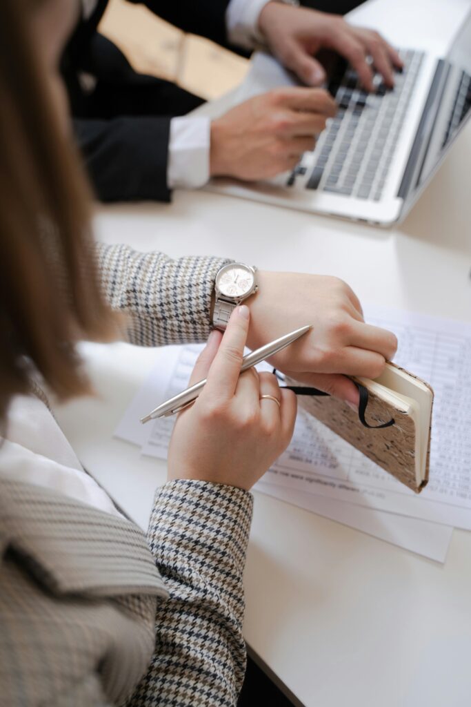 Business professionals at a meeting reviewing notes and checking time.