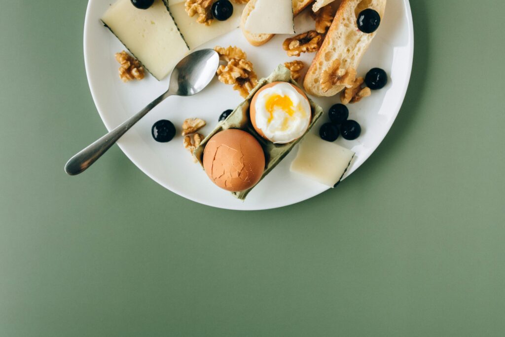 A delicious assortment of breakfast items including cheese, soft boiled egg, and walnuts on a stylish plate.