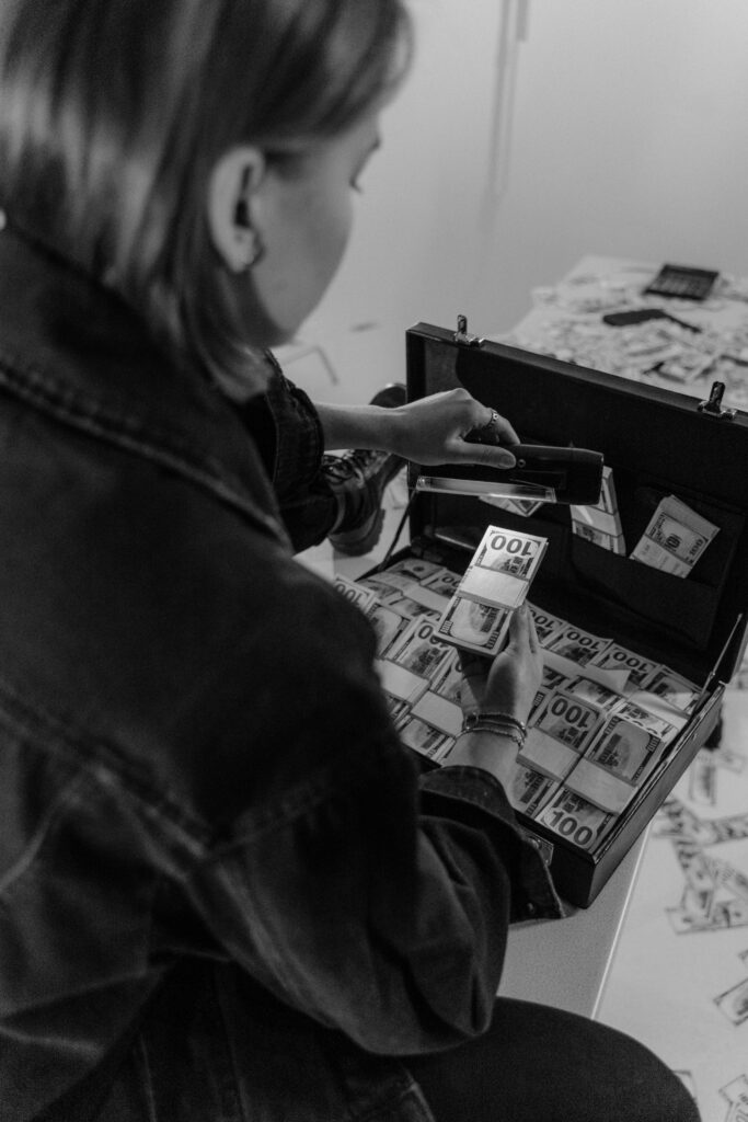 Person using ultraviolet light to inspect bills for authenticity in a monochrome setting.