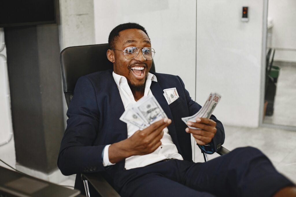 Joyful businessman in suit holding dollar bills, symbolizing success and financial achievement.
Rich vs Successful – Difference