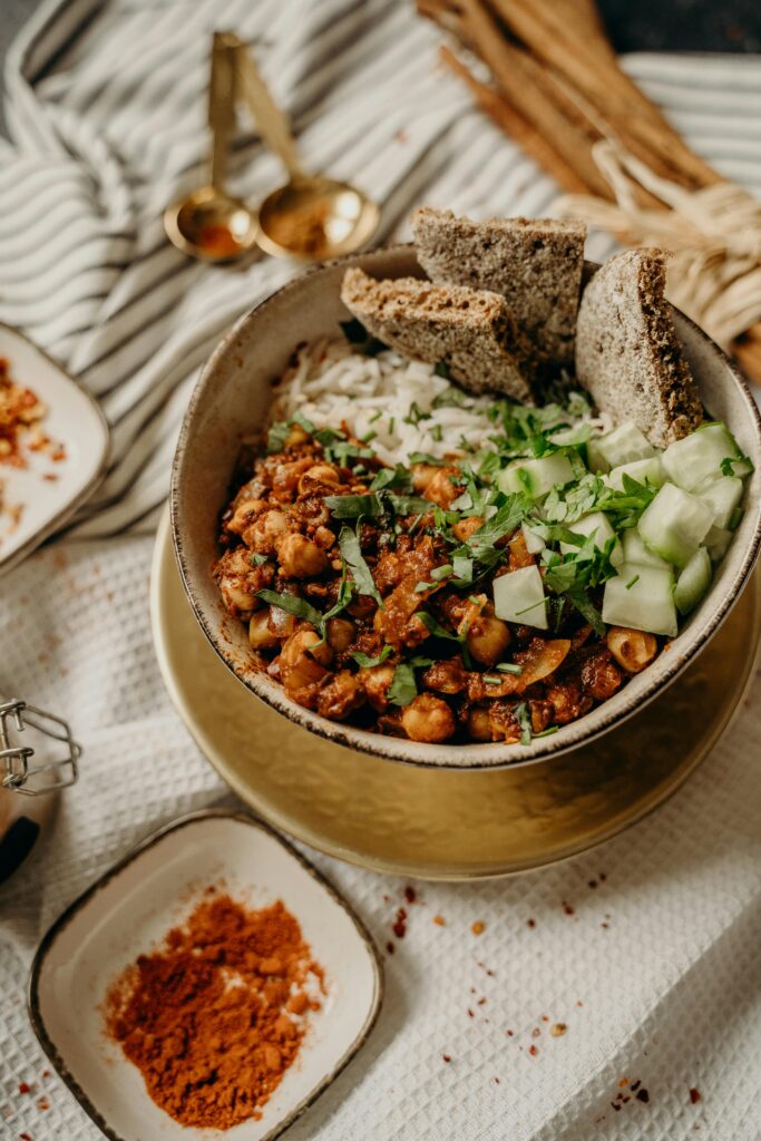 Delicious vegan bowl featuring chickpeas, rice, cucumber, and bread, perfect for a healthy meal.