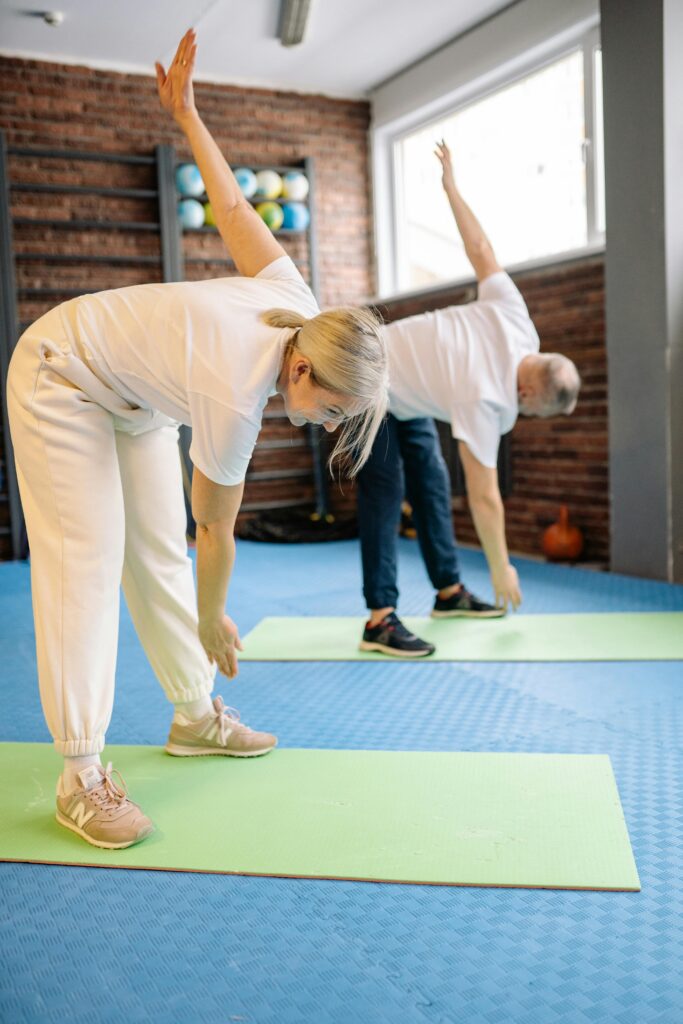 Senior adults stretch on mats in a fitness gym, promoting a healthy lifestyle.