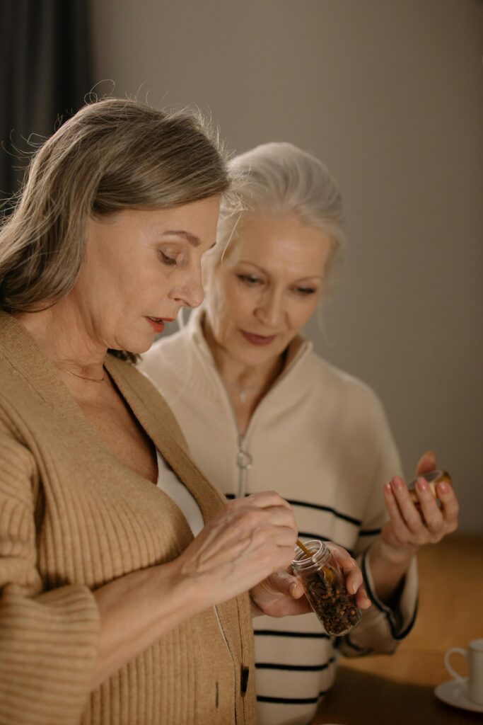 Two senior women enjoying tea together in a warm and inviting kitchen setting.