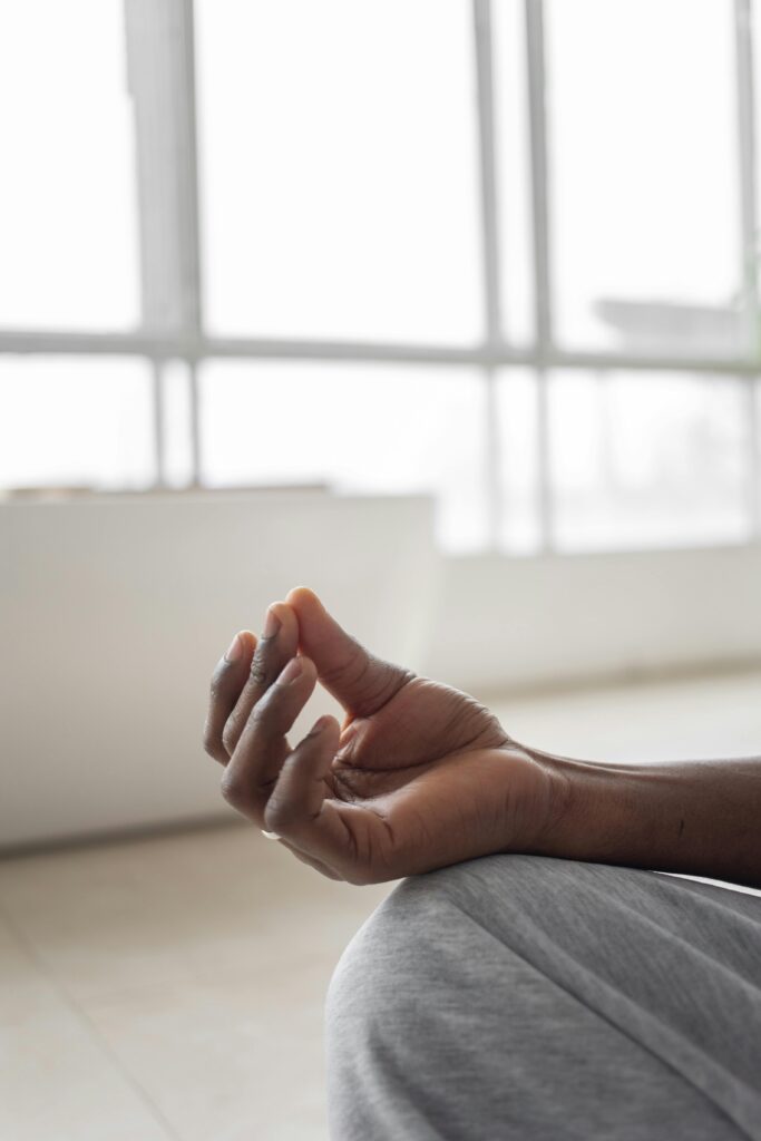 Person practicing meditation indoors with a focus on hand gesture for relaxation and mindfulness.