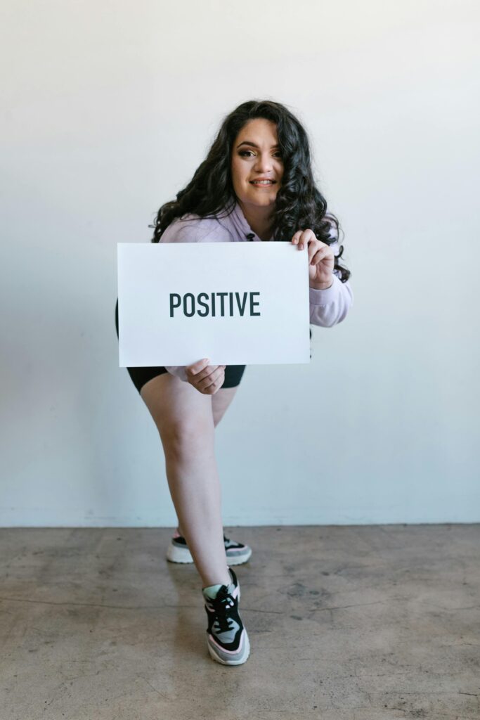Portrait of a confident plus-size woman holding a 'Positive' placard, promoting self-love.