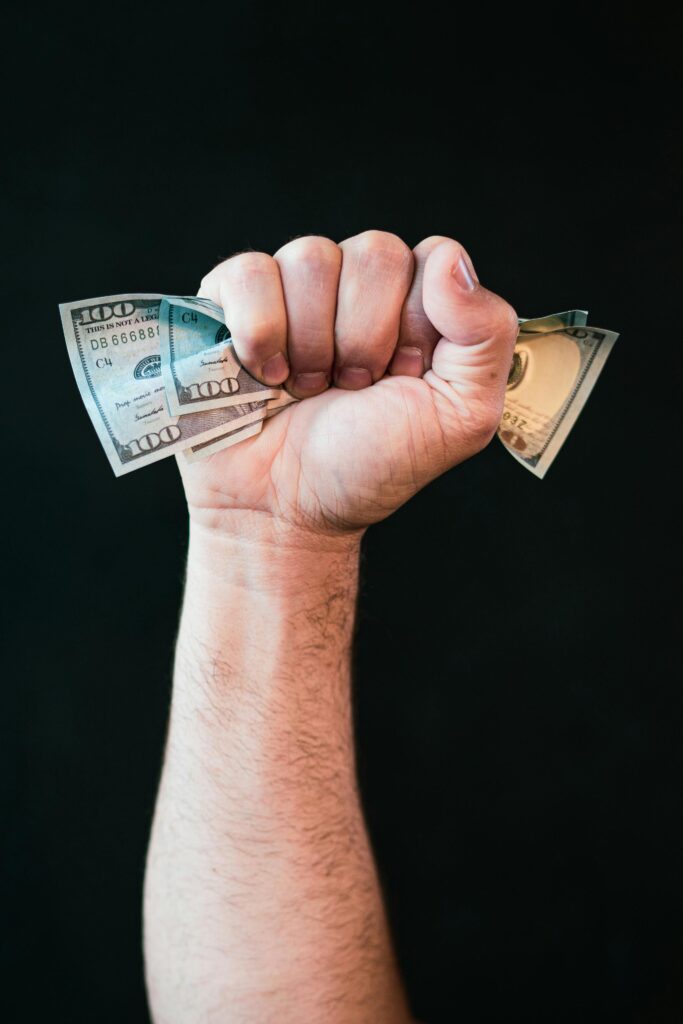 Close-up of a fist holding US dollars on a black background symbolizing financial strength.