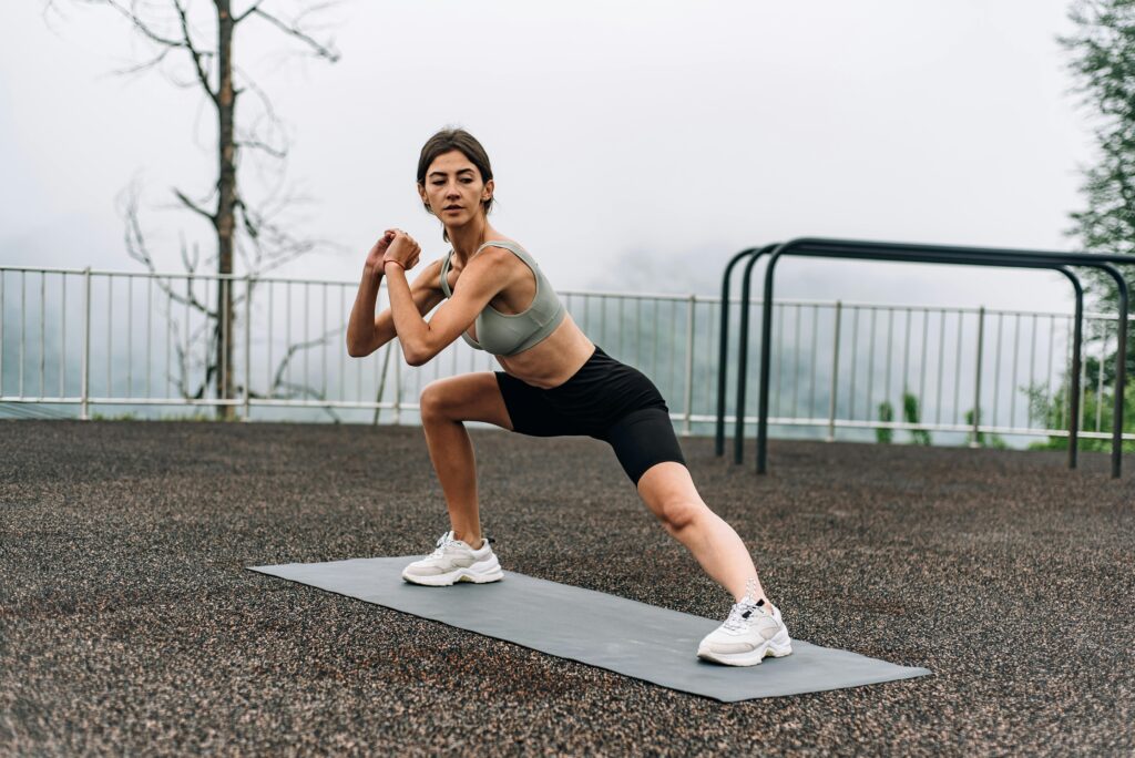 Woman exercising outdoors on yoga mat with a scenic view, embracing a healthy lifestyle.