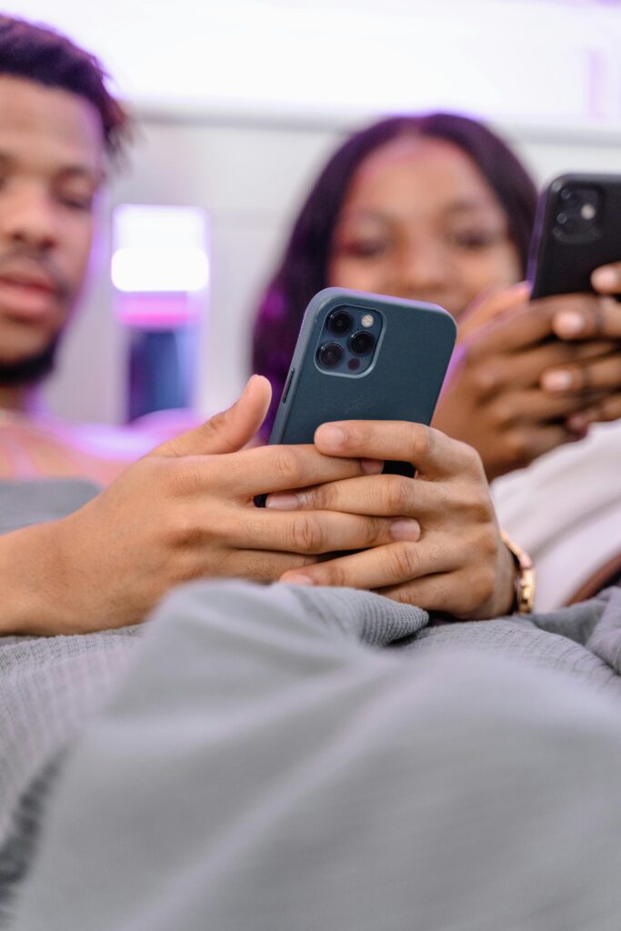 A couple relaxes in bed using their smartphones, enjoying leisure time together.