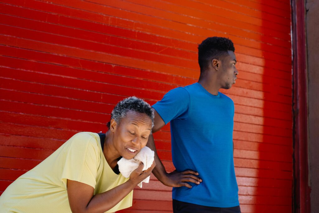 Two adults cooling down after exercise against a vibrant red wall, emphasizing an active lifestyle.