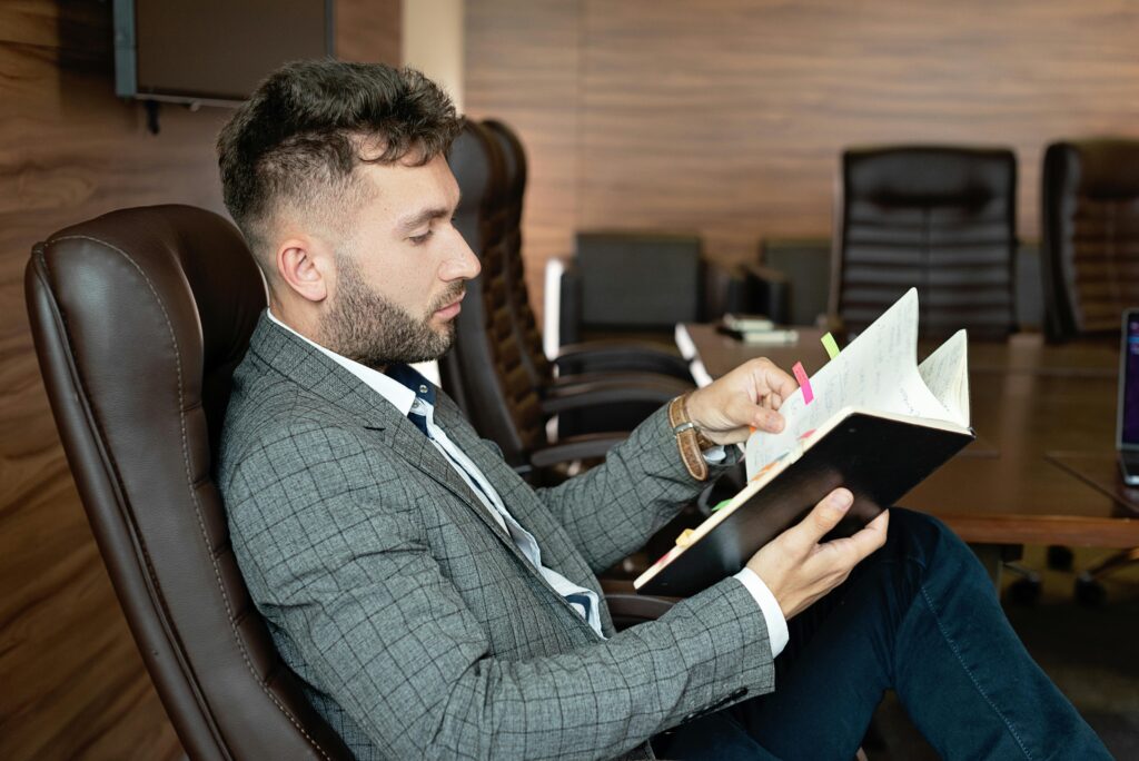 Professional businessman in formal attire reviewing notes in a modern office environment.