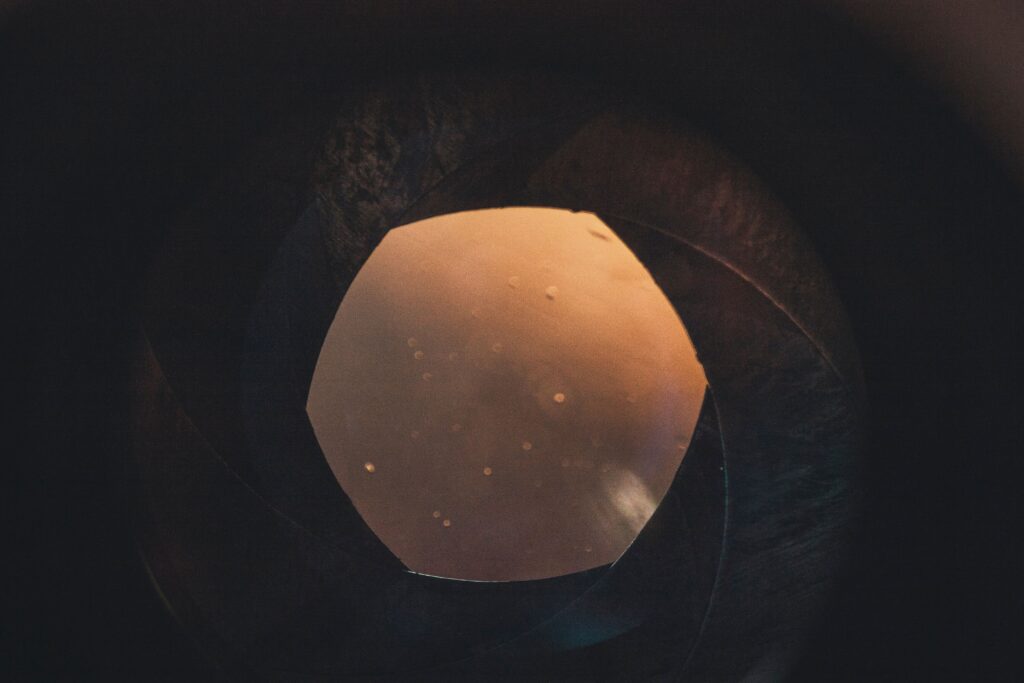 An artistic look inside a camera lens with warm glow and circular bokeh.