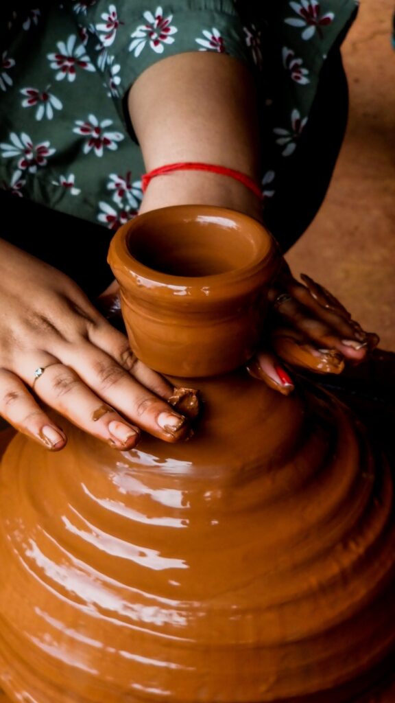 Close-up of hands shaping a clay pot in an artisan pottery workshop, showcasing craftsmanship.