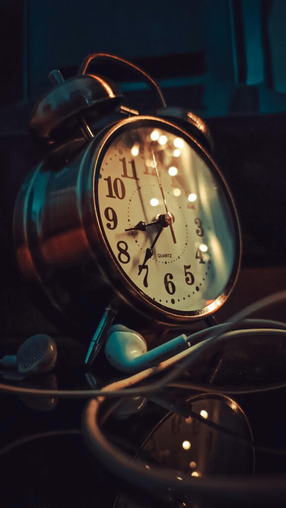 Classic vintage alarm clock with warm lighting and earphones, reflecting a cozy ambiance.