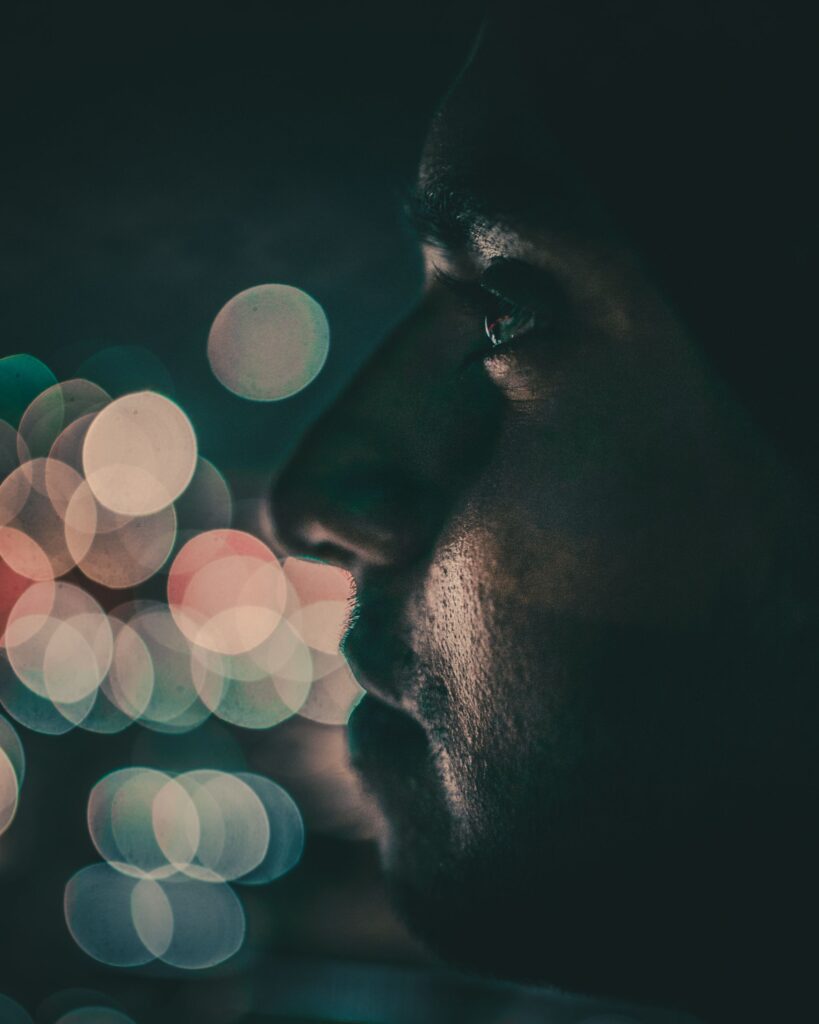 Atmospheric side profile of a man with colorful bokeh lights at night.