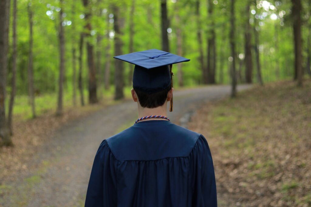 Graduate walking through a serene forest path, symbolizing new beginnings.
