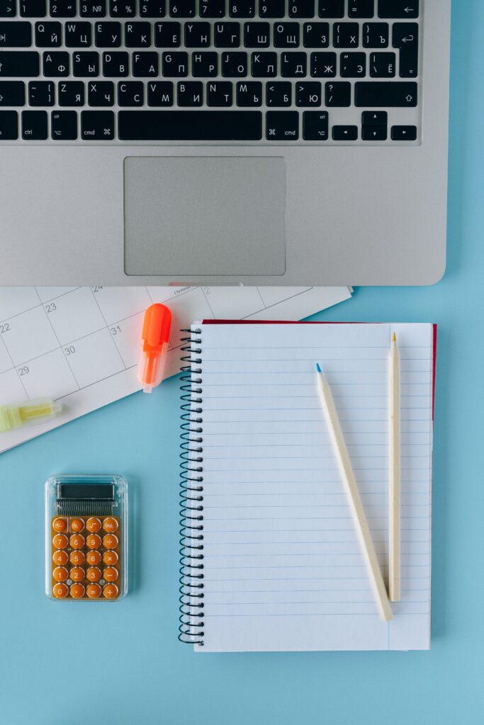 Image of a neat workspace with a laptop, calendar, and stationery items.