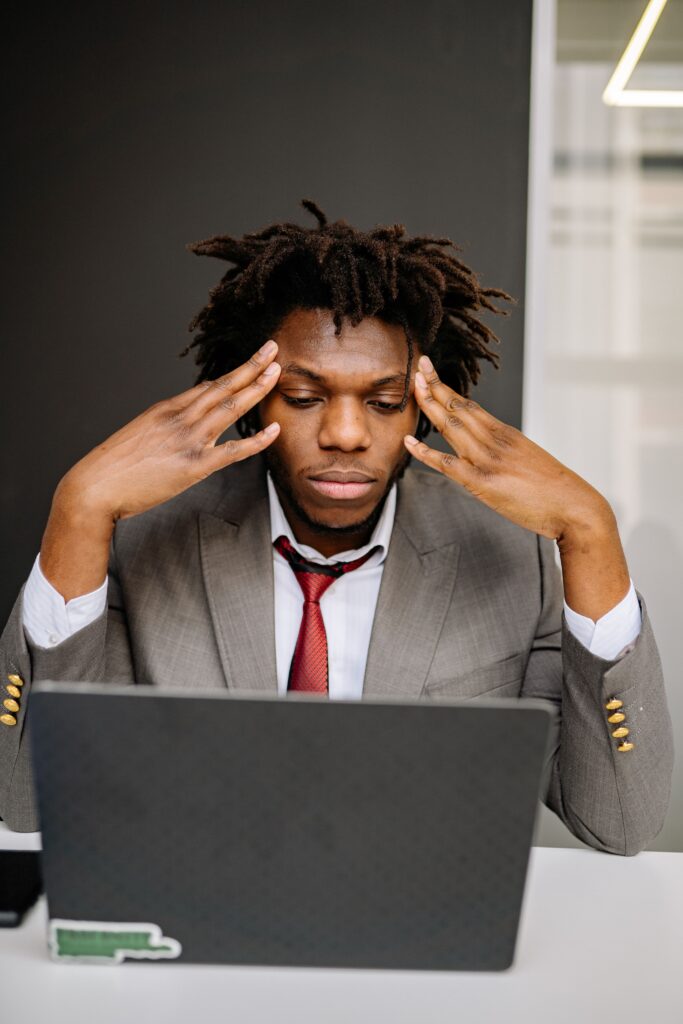A business professional experiencing stress at work while using a laptop in an office.