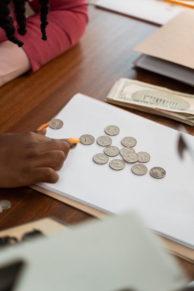 Close-up of diverse hands counting coins on a wooden table, highlighting teamwork and finance.