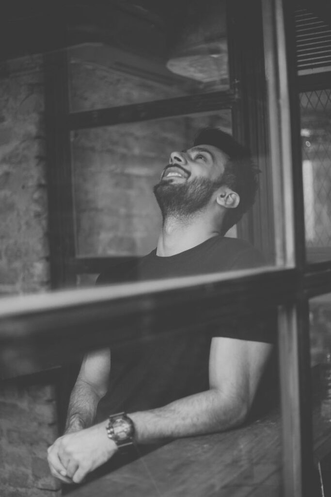 Artistic black and white portrait of a man laughing in an industrial setting.