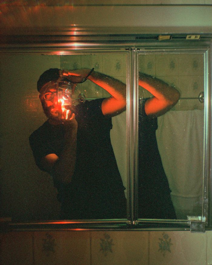 Artistic self-portrait featuring a reflection in a mirror with moody lighting.