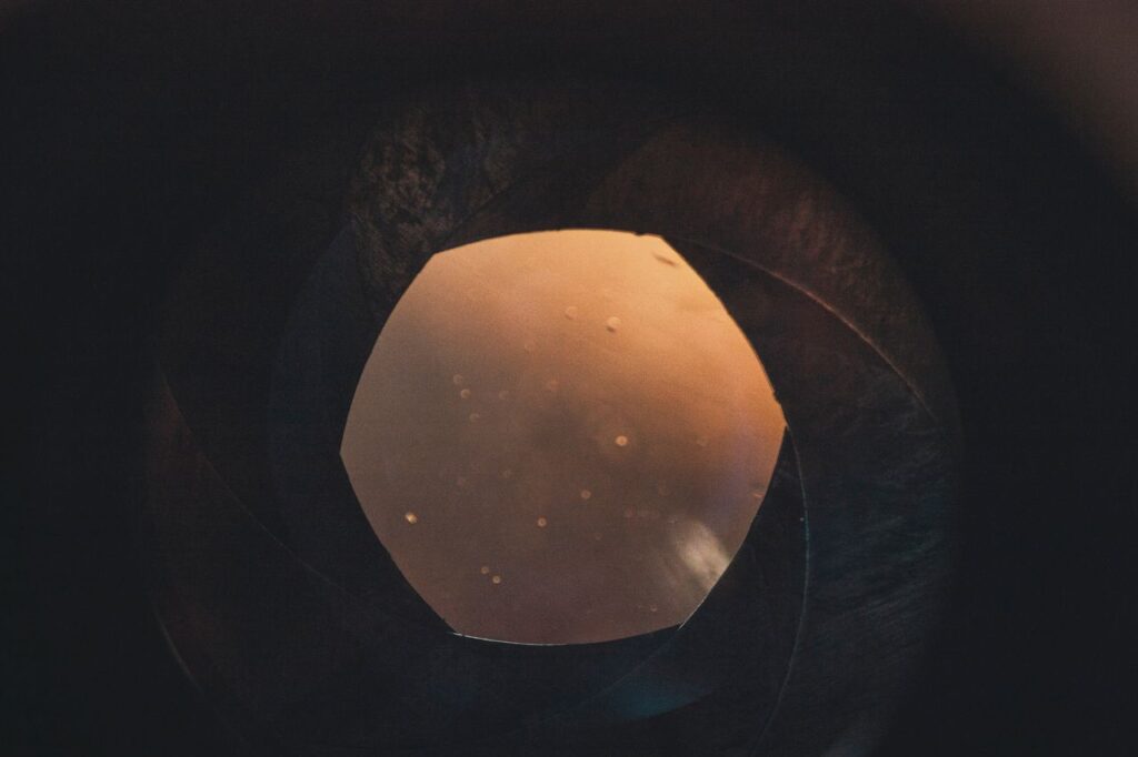 An artistic look inside a camera lens with warm glow and circular bokeh.