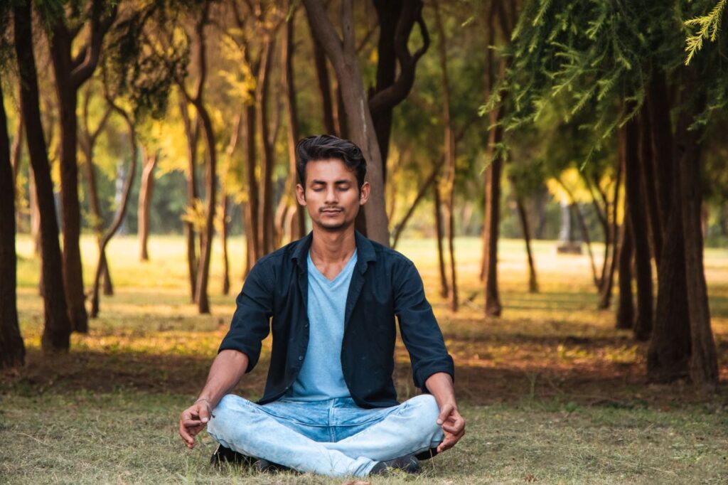 Man meditating peacefully in a lush forest in Lucknow, UP, India.