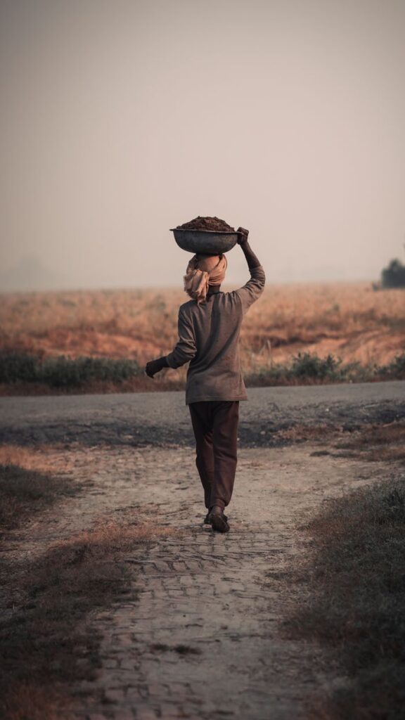 A rural man carrying a basket on his head walks along a cobblestone path at dusk.
Mental Toughness Kaise Develop Kare