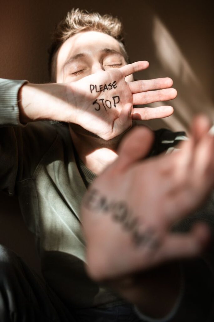 A young man covering his face with hands, displaying messages of distress and a plea to stop. Victim Mindset Se Bahar Kaise Nikle